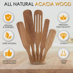 Op de afbeelding: Een set van vijf acaciahouten keukengerei, waaronder spatels en een sleuflepel. De keukengerei zijn gemarkeerd met "AKRILANE". De afbeelding bevat de tekst "ALL NATURAL ACACIA WOOD", "STRONG & DURABLE" en "100% NATURAL".