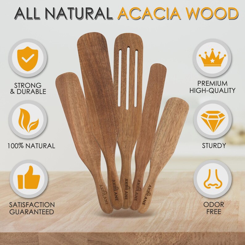 Op de afbeelding: Een set van vijf acaciahouten keukengerei, waaronder spatels en een sleuflepel. De keukengerei zijn gemarkeerd met "AKRILANE". De afbeelding bevat de tekst "ALL NATURAL ACACIA WOOD", "STRONG & DURABLE" en "100% NATURAL".