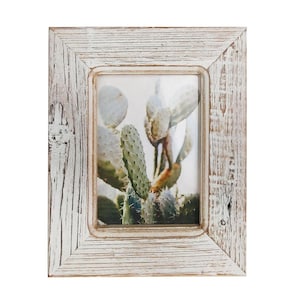 May include: A rectangular, distressed white wooden picture frame with a cactus print. The frame has a rustic, weathered appearance, with visible wood grain and a slightly off-white color. The image inside features a close-up of a green cactus.