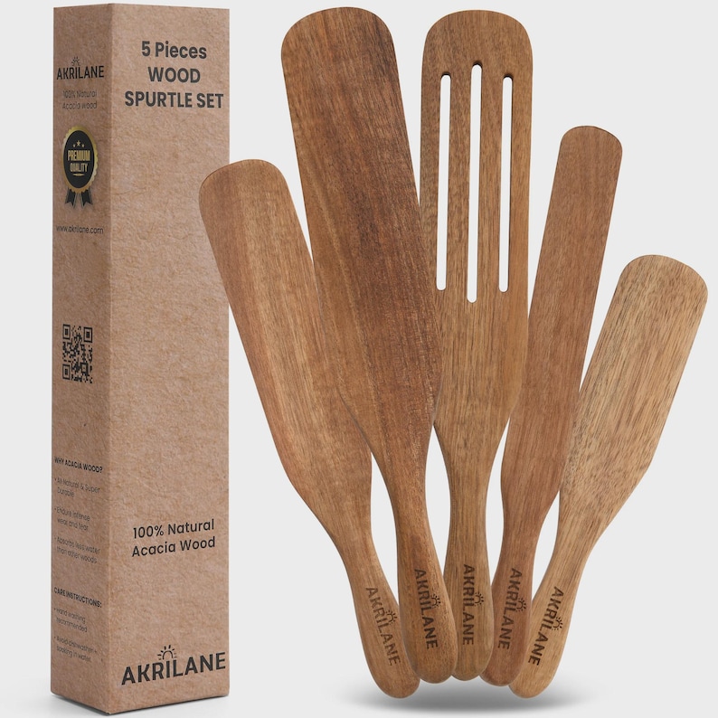 Op de afbeelding: Een set van vijf houten spatels en een sleufspatel van acaciahout. De spatels hebben verschillende vormen en maten, met de merknaam "AKRILANE" op de handvatten. De set wordt geleverd in een kartonnen doos.