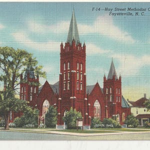 May include: Vintage postcard featuring the Hay Street Methodist Church in Fayetteville, N.C. The church is a large brick structure with multiple spires and a tall central tower. The sky is blue with scattered clouds, and trees frame the church.