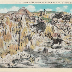 May include: Vintage postcard featuring a colorful landscape of Hell's Half Acre in Wyoming. The image showcases layered rock formations in shades of tan, yellow, and red, under a blue sky with clouds. The text "1123 Scene in the Bottom of Hell's Half Acre - Powder River, Wyoming" is visible.