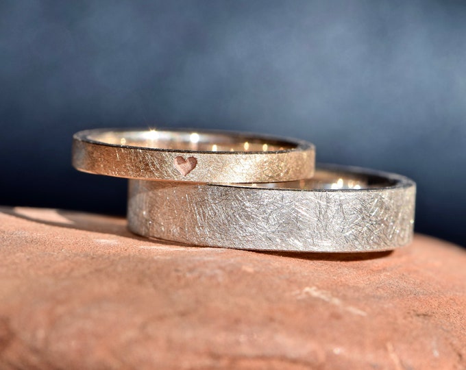 Simple rose gold and silver wedding rings with an engraved heart