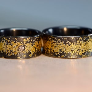 Schwarze Eheringe mit Diamant und Gold aus der Serie *Sternenstaub*