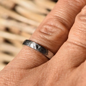 May include: A silver hammered band ring with a heart design.