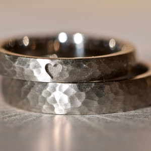May include: Two silver hammered wedding bands with a heart cutout detail.