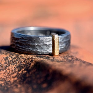 Black ring made of silver hammered with red gold