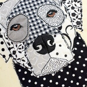 May include: Black and white patchwork fabric dog applique with embroidered eyes and nose. The dog is wearing a black and white polka dot bandana.