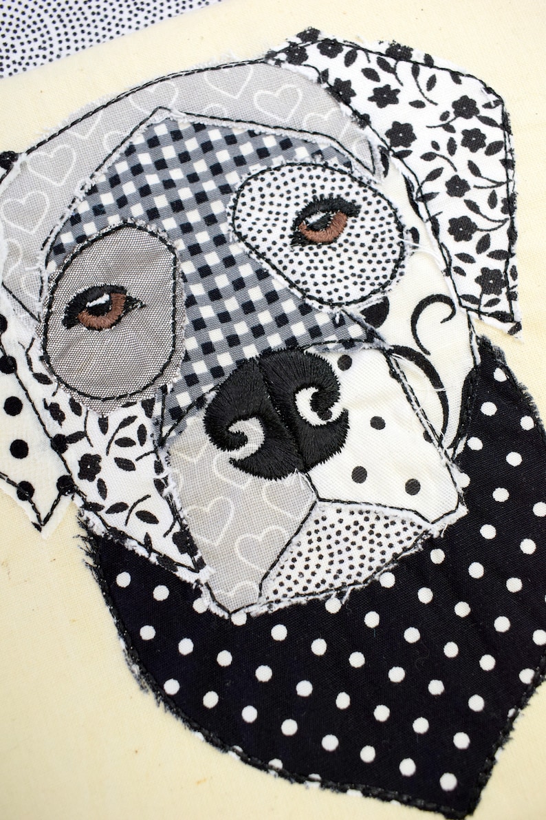 May include: Black and white patchwork fabric dog applique with embroidered eyes and nose. The dog is wearing a black and white polka dot bandana.