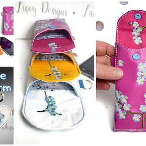 May include: Four phone cases with different colored leather and floral embroidery. The cases are stacked on top of each other. The top case is pink with blue flowers. The second case is yellow with blue flowers. The third case is white with blue flowers. The bottom case is brown with blue flowers. The cases are all closed. There is a free charm included, which is a white heart with blue flowers.