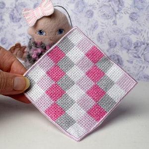 Op de afbeelding: Een vierkant stuk stof met roze, grijze en witte ruitjes en een roze rand.