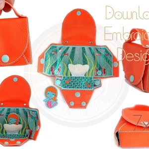 May include: An orange fabric purse with a mermaid and seashell design. The purse is folded open to show the inside. The purse has a handle and a flap that closes with a button. Download Embroidery Design 7x7.