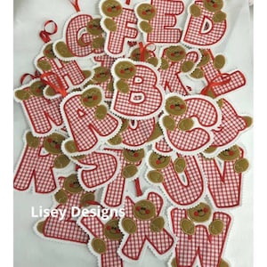 May include: A set of 26 gingerbread man alphabet ornaments. Each ornament is made of red and white gingham fabric with a gingerbread man design. The ornaments are perfect for decorating a Christmas tree or adding a festive touch to any room.