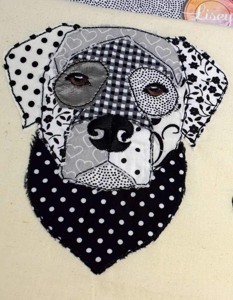 May include: Black and white patchwork fabric dog applique with a black and white polka dot bandana. The dog's eyes are brown and the fabric is sewn together in a variety of patterns.