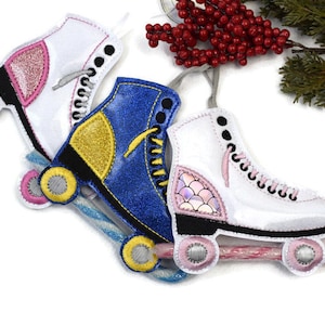 May include: Three roller skate ornaments, one white with pink glitter, one blue with gold glitter, and one white with a pink and iridescent mermaid scale design.