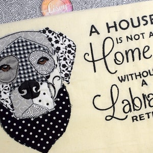 May include: A black and white patchwork Labrador Retriever dog head with a black and white polka dot bandana. The text "A house is not a home without a Labrador Retriever" is embroidered on a cream background.