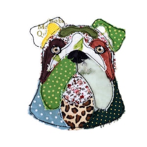 Könnte beinhalten: Ein bunter Patchwork-Bulldoggenkopf aus verschiedenen Stoffen. Das Gesicht des Bulldogs ist weiß mit braunen Augen, einer schwarzen Nase und einer grünen, braunen und roten Patchwork-Nase.