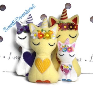 Puede incluir: Un conjunto de tres juguetes de peluche de unicornio con coronas florales bordadas y corazones. Los unicornios son amarillos, blancos y blancos con detalles rosas.