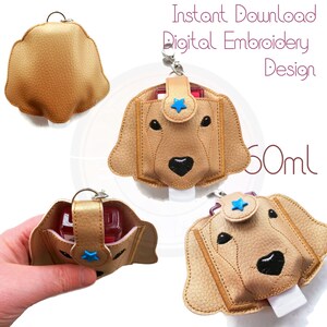 Könnte beinhalten: Ein digitales Stickmuster für einen 60 ml Handdesinfektionsmittel-Halter mit einem niedlichen Golden Retriever-Gesicht. Das Design enthält einen blauen Stern und ist perfekt, um ein personalisiertes und praktisches Accessoire zu erstellen.