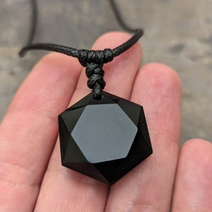 May include: Black obsidian star of David pendant necklace on a black cord.