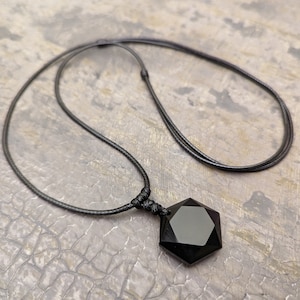 May include: A black onyx pendant necklace with a seven-pointed star shape, hanging from a black cord.