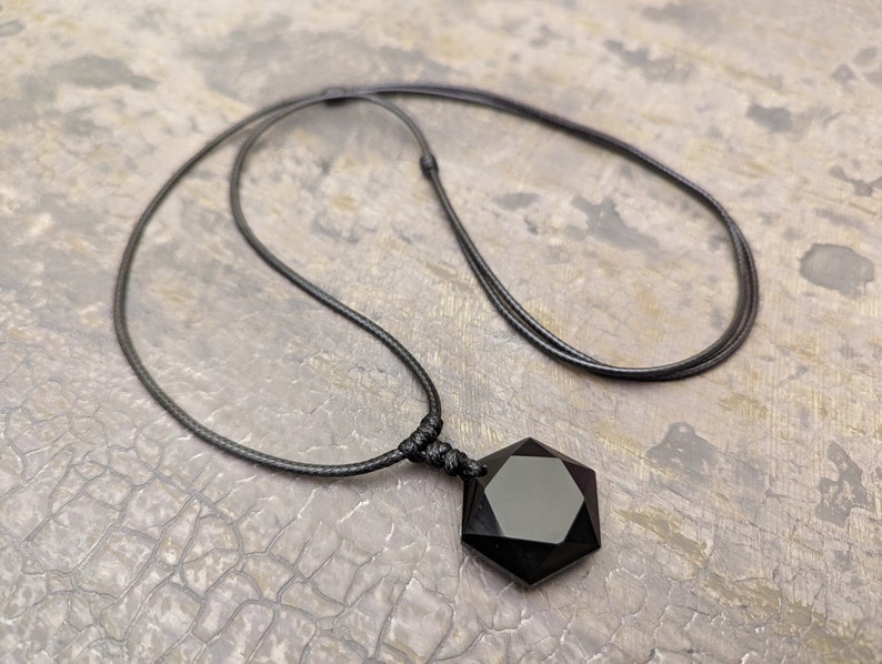 May include: A black onyx pendant necklace with a seven-pointed star shape, hanging from a black cord.