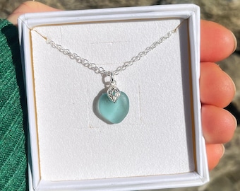 May include: A silver chain necklace with a light blue sea glass heart pendant. The pendant has a silver filigree design.
