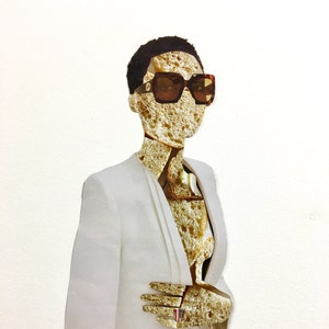 May include: A white blazer with a person's face and body obscured by slices of bread. The person is wearing sunglasses and a ring with a small American flag.