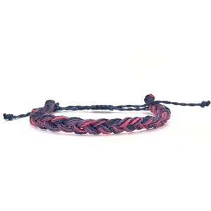 Könnte beinhalten: Ein geflochtenes Armband mit rosa und blauen Fäden.