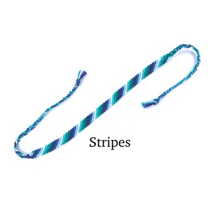 Puede incluir: Un brazalete de amistad azul, blanco y verde con la palabra "Stripes" impresa debajo.