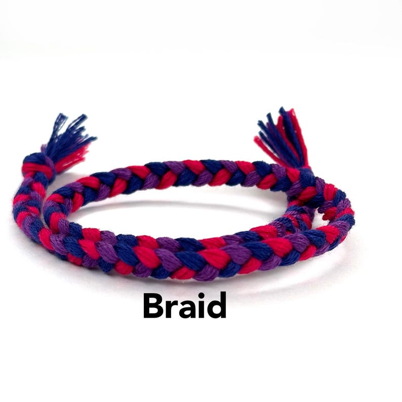 May include: A braided bracelet in pink, purple, and blue colors. The bracelet is made of woven string and is called "Braid".