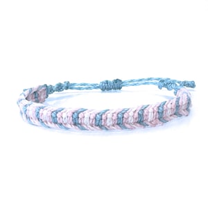 May include: A handmade macrame bracelet in a flat braid design. The bracelet features a repeating pattern of light blue, pink, and white threads. The adjustable closure is light blue. This bracelet is a stylish accessory.