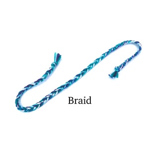 Puede incluir: Un cord&oacute;n trenzado con hilos blancos, azul verdoso y azul oscuro. El cord&oacute;n est&aacute; anudado en un extremo y tiene extremos sueltos en el otro. El texto "Braid" est&aacute; escrito debajo del cord&oacute;n.