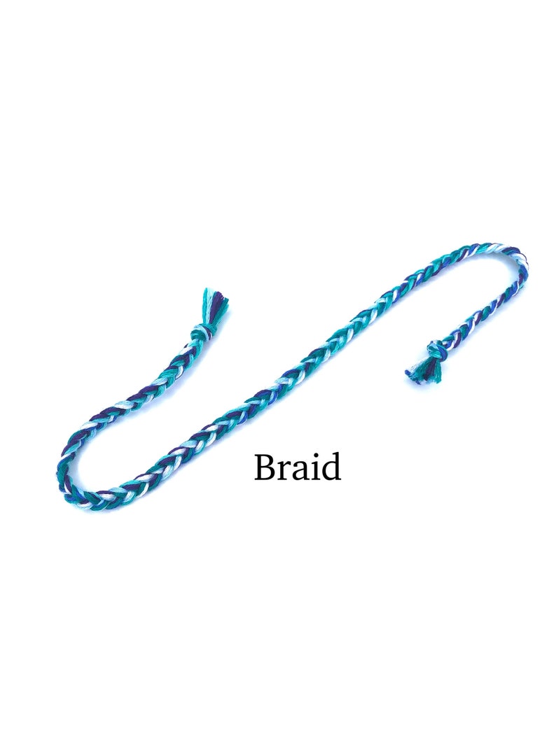 Puede incluir: Un cord&oacute;n trenzado con hilos blancos, azul verdoso y azul oscuro. El cord&oacute;n est&aacute; anudado en un extremo y tiene extremos sueltos en el otro. El texto "Braid" est&aacute; escrito debajo del cord&oacute;n.