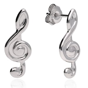 Puede incluir: Un par de pendientes plateados con forma de clave de sol. Los pendientes tienen una superficie pulida y reflectante y un diseño clásico de nota musical. Se muestran sobre un fondo blanco.