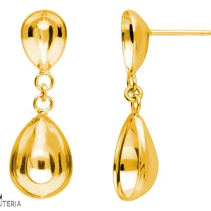 Pode incluir: Um par de brincos pendurados dourados. Cada brinco apresenta um design em forma de gota, conectado por pequenos anéis. Os brincos têm uma superfície polida e reflexiva, e um pino para orelhas furadas.