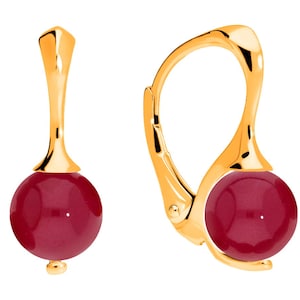 Può includere: Un paio di orecchini color oro con chiusura a leva. Ogni orecchino presenta una perla rotonda e lucida di colore rosso scuro. Gli orecchini hanno un design semplice ed elegante, con una finitura liscia e lucida.