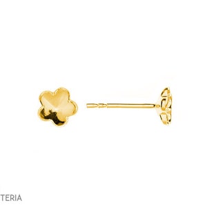 Pode incluir: Um par de brincos de botão dourados em forma de flor. Um brinco está posicionado na vertical, mostrando o pino e a parte de trás da flor. O outro brinco está virado para cima, mostrando as pétalas da flor. Os brincos estão em fundo branco.