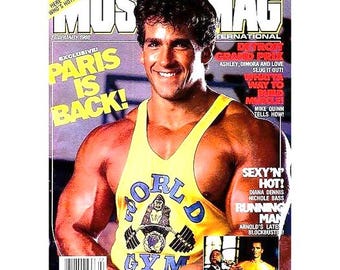 Peut inclure: Une couverture de magazine mettant en scène un homme musclé portant un débardeur jaune avec un logo bleu "World Gym". Le magazine est intitulé "MusMag International" et la couverture présente le texte "Paris is Back!" et "Detroit Grand Prix".