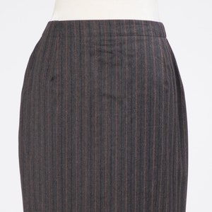 May include: A dark gray skirt with thin, vertical, brown stripes. The skirt is knee-length and has a straight silhouette.
