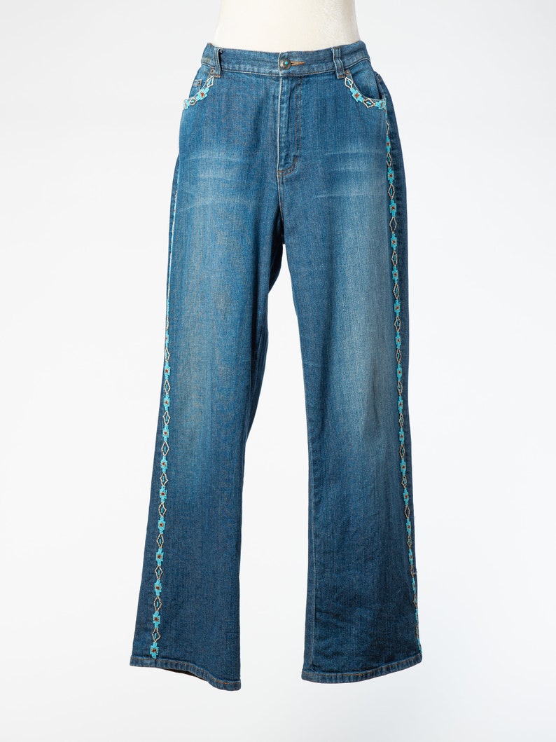 May include: Blue denim jeans with a turquoise and white embroidered design along the sides.