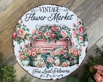 Puede incluir: Señal vintage de "Mercado de flores" con un camión rosa lleno de rosas rosas sobre un fondo blanco. La señal también dice "Entregas locales gratuitas".