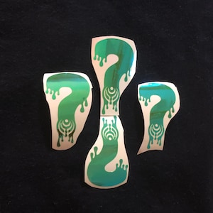May include: Four iridescent green question mark stickers with a dripping effect. Each sticker features a stylized symbol in the center.