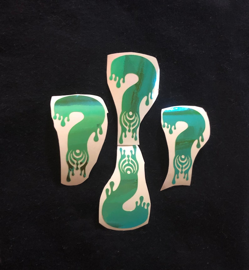 May include: Four iridescent green question mark stickers with a dripping effect. Each sticker features a stylized symbol in the center.
