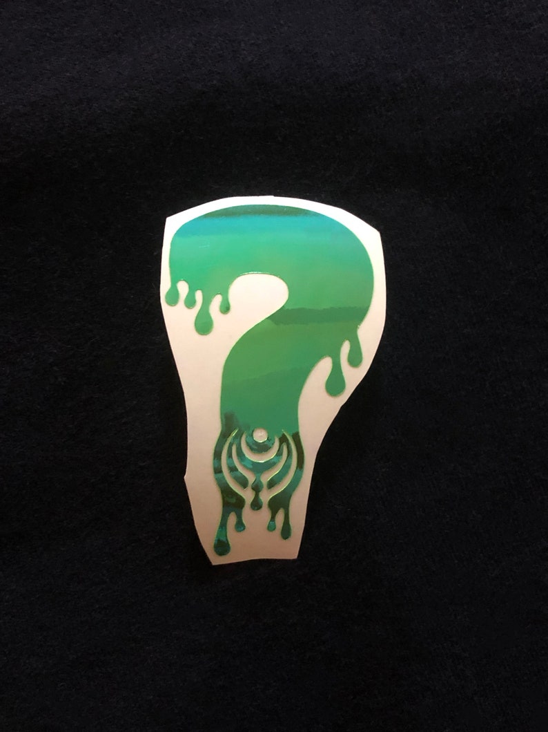 May include: A green and blue sticker with a dripping question mark design. The question mark has a stylized pattern inside.