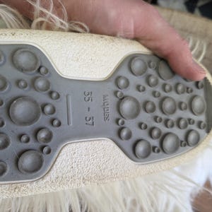 Puede incluir: Primer plano de la suela de un zapato, con una suela de goma gris texturizada con patrones circulares de varios tama&ntilde;os. La parte superior del zapato es blanquecina. La talla 35-37 es visible.