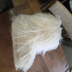 Puede incluir: Una bota cremosa y peluda con suela beige. La bota tiene un aspecto desgre&ntilde;ado y texturizado, con fibras largas y suaves. La suela parece estar hecha de un material liso y de color claro. La bota est&aacute; dise&ntilde;ada para brindar calidez y comodidad.