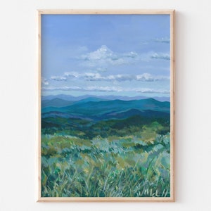 May include: An original landscape painting featuring a mountain range under a blue sky with white clouds. The foreground shows green and yellow grassy vegetation. The artwork is framed in a light wood frame.