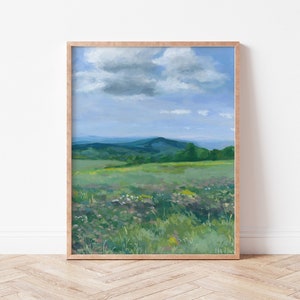 May include: A framed painting of a landscape with a field of wildflowers in the foreground, a rolling green hill in the middle ground, and a blue sky with a single white cloud in the background.