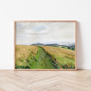 May include: A watercolor painting of a green path winding through a field of golden wheat. The path leads to a distant view of rolling hills and a cloudy sky.